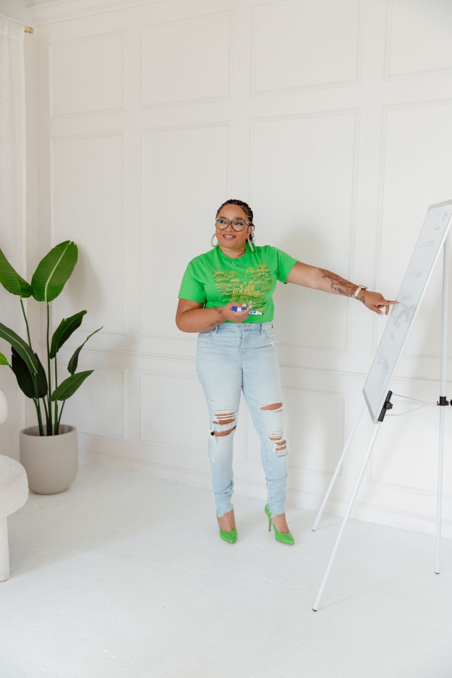 Coach Tara Tucker teaching at a whiteboard in the I Am Becoming T-shirt