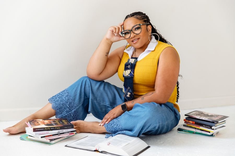 Coach Tara Tucker seated among books she has written and published, with an open Bible