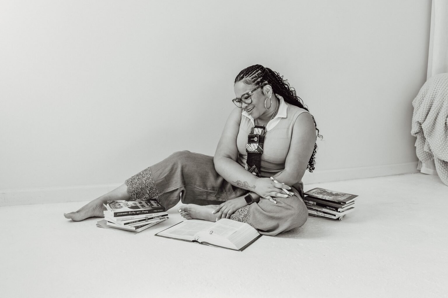 Coach Tara Tucker reading, surrounded by books, in black and white